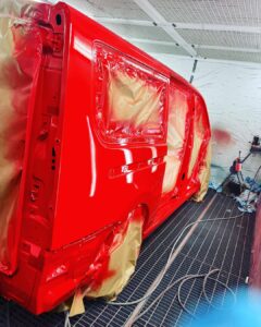 Lakierowanie samochodu w profesjonalnej kabinie lakierniczej – świeżo polakierowany czerwony van